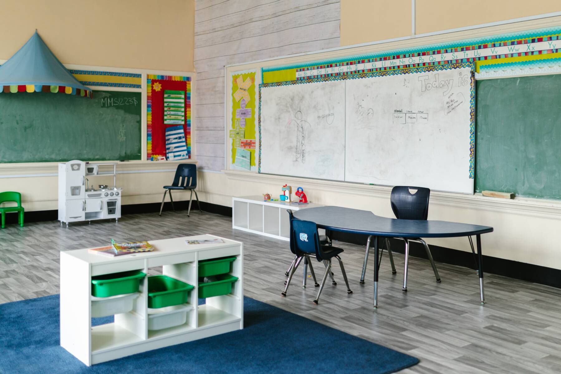A classroom with a desk, chalkboard and flooring by Diverzify