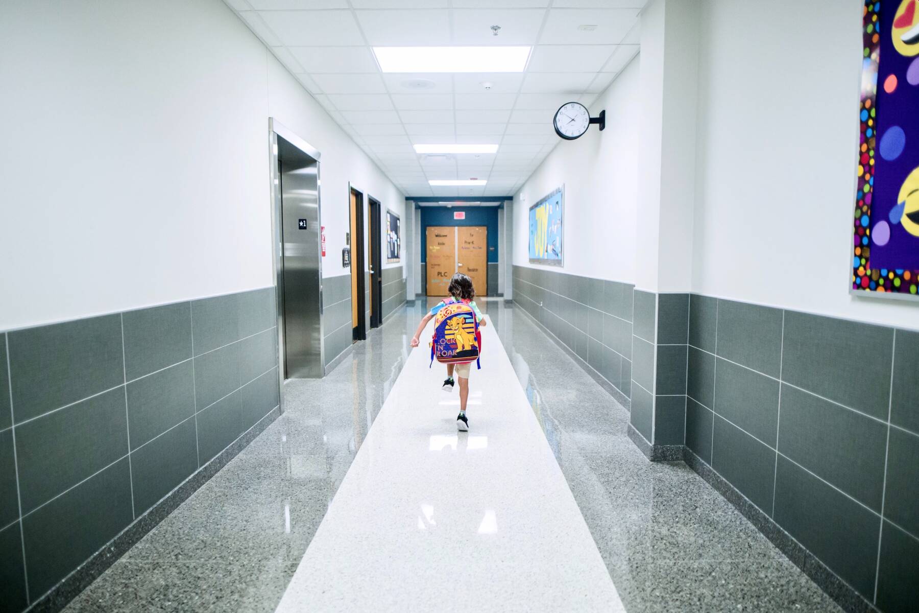 A school student walking the hallways that contain the contrast of dark gray and white marble flooring